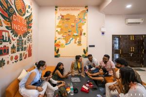 a group of people sitting around a table in a room at Zostel Indore in Indore +68 photos