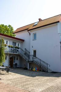 a white building with stairs and a patio at Pokoje i apartamenty Pod Dębem in Rowy