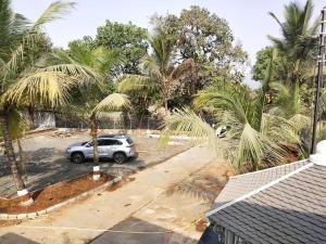 un'auto parcheggiata in un parcheggio con palme di Malhar Baug Resort a Nagaon 1 altra foto