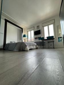 a bedroom with a bed and a desk and two windows at Le 27 Deauville in Deauville