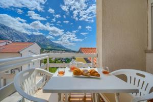 a table with bread and drinks on a balcony with mountains at Villa LeMar in Baška Voda