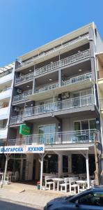a large apartment building with tables in front of it at Guest house WEST in Sunny Beach