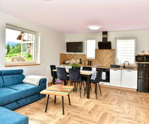 a living room with a blue couch and a kitchen at Szarotka in Stronie Śląskie