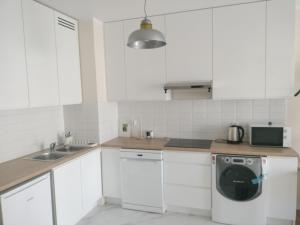 a kitchen with white cabinets and a washing machine at Quiet in the City Wrocławska in Kraków