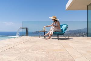 a woman sitting in a chair next to a table at Villas Aloe Vera by Abahana Luxe in Benitachell