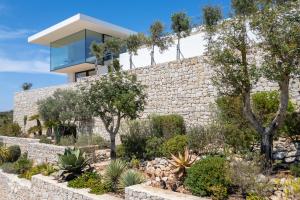 a house with a stone wall and a garden at Villas Aloe Vera by Abahana Luxe in Benitachell