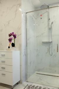 a white bathroom with a shower and a white dresser at Luxus Apartman in Nyíregyháza
