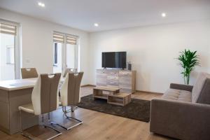 a living room with a table and chairs and a television at Luxus Apartman in Nyíregyháza