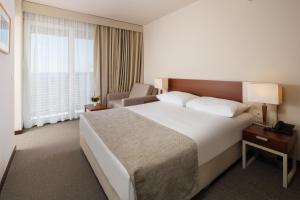 a hotel room with a large bed and a chair at Hotel Albatros Plava Laguna in Poreč