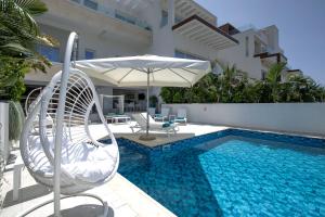 a pool with two chairs and an umbrella next to a pool at Olymp Luxury House - Ultra Luxury Beachfront Villa with Rooftop Lounge in Paphos +112 photos