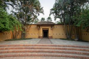 a building with stairs and palm trees in front of it at Unnati Cultural Village Hospitality in Maruwā Ghāt