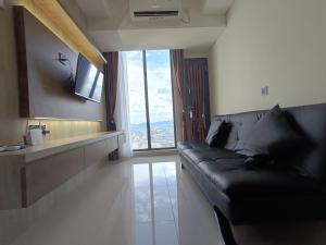 a living room with a black leather couch and a window at 2BR Pollux Habibie Meisterstadt Tower 1 Batam City in Batam Center