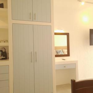 a white cabinet in a room with a mirror at Traditional dream myconian studio in Ornos