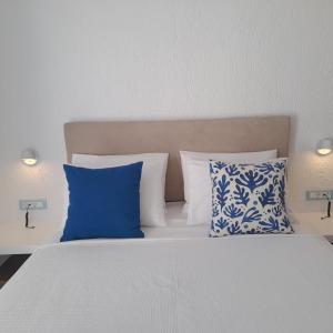 a bed with blue and white pillows in a bedroom at Traditional dream myconian studio in Ornos +36 photos