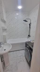 a white bathroom with a sink and a tub and a toilet at Salamatina Recidence in Yakkasaray