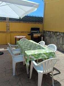 una mesa con sillas blancas y una sombrilla blanca en El Hogar de Pepe, en El Casar de Escalona