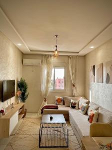 a living room with a couch and a table at Appartement cosy 2 min aéroport Marrakech 2 chambres bien équipé in Marrakech