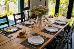 a wooden table with glasses of wine and a vase of flowers at SaffronStays Ibiza - 4BR Nerul villa, glass-bottom pool into living, ensuite rooms, rooftop party zone near Candolim in Nerul