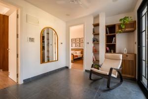 a living room with a chair and a mirror at SaffronStays Ibiza - 4BR Nerul villa, glass-bottom pool into living, ensuite rooms, rooftop party zone near Candolim in Nerul