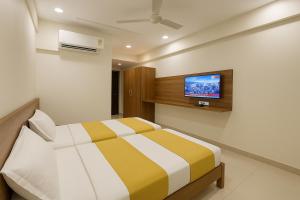 a bedroom with a bed and a tv on the wall at StayGuru Hari Om Residency in Bhuj