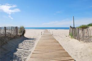 a wooden pathway to the beach with the ocean in the background at Le Patio de Santa Monica, 5 minutes from the sea, 2 stars in Pérols