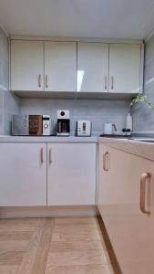 a white kitchen with white cabinets and appliances at Haenarr Hanok Stay in Mandarin Orchard, 100m from Sea in Seogwipo +21 photos