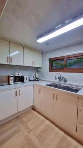 a kitchen with white cabinets and a sink at Haenarr Hanok Stay in Mandarin Orchard, 100m from Sea in Seogwipo