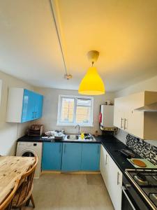 a kitchen with blue cabinets and a yellow light at Mile-End Staycation in London