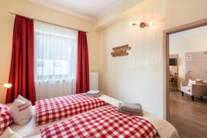 1 dormitorio con 2 camas y una ventana con cortinas rojas en Komfort Apartment Römersberger - 4, en Vogtareuth