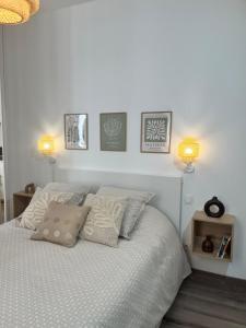 a bedroom with a white bed with pillows and two lights at Loft au cœur de Tarare in Tarare