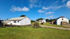 a couple of white buildings in a field at Newgale Lodge in Newgale