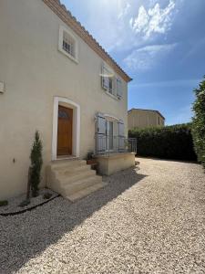 a white house with a brown door and stairs at Maison LARLY Arles Swimming pool in Arles