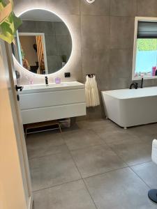 a bathroom with a tub and a sink and a mirror at Entire home with pool and garden in Ålesund