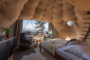 a bedroom with a bed and a large window at Tatra Glamp Tarasówka - Sieć noclegowa Tatra Glamp in Poronin