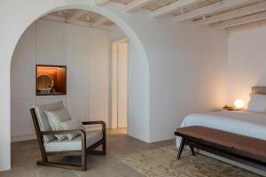 Un dormitorio con una cama, una silla y una mesa. en Blue Rock Villa, en Playa Kalo Livadi
