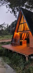 eine kleine Hütte mit zwei Stühlen auf einer Holzterrasse in der Unterkunft Chalé Riacho - Cabana em Contenda - Chalé romântico com hidromassagem in Contenda + 27 Fotos