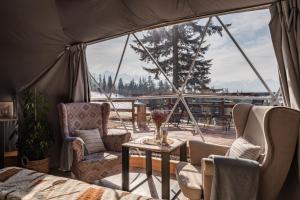 a room with two chairs and a table and a tent at Tatra Glamp Tarasówka - Sieć noclegowa Tatra Glamp in Poronin