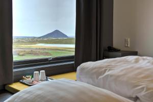 a bed sitting in front of a window next to a window at Hótel Laxá in Myvatn