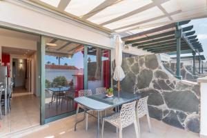 Un patio con mesa y sillas y un muro de piedra. en Brisa del Sur, en Maspalomas