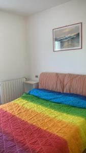 a bed with a rainbow colored blanket on it at valle del paradiso 9 in Seggiano