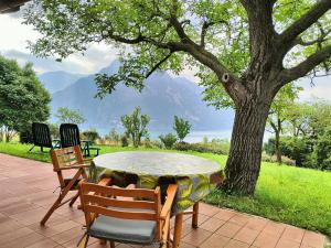 una mesa y sillas en un patio con un árbol en IseoLakeRental - La Casina, en Riva di Solto