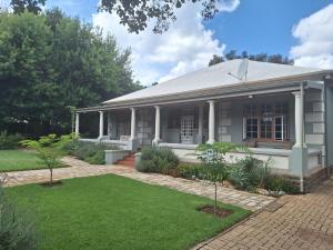 an old house with a lawn in front of it at Oude Post Guesthouse and Cottage - The Old Postmaster's House in Lydenburg