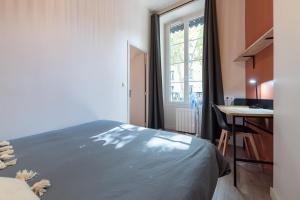 une chambre avec un lit, un bureau et une fenêtre dans l'établissement Let's- 2 and 1 - Sweet Voltaire, à Lyon