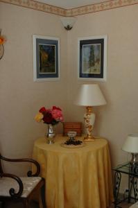 een tafel met een lamp en een vaas met bloemen erop bij Le Jardin de Roses DOMINIQUE LOREAU in Saint-Bonnet-de-Mure