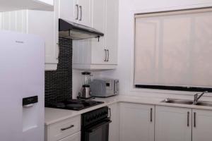 a kitchen with white cabinets and a stove top oven at The Residence Apartments in Nyanda +12 photos