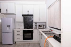 a white kitchen with a sink and a refrigerator at The Residence Apartments in Nyanda
