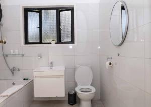 a bathroom with a toilet and a sink and a mirror at The Residence Apartments in Nyanda