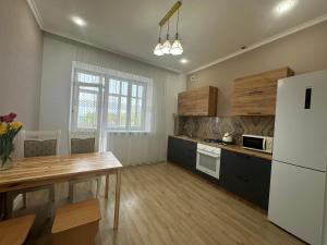 a kitchen with a wooden table and a refrigerator at Park home Uralsk in Uralsk