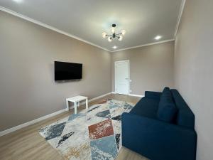 a living room with a blue couch and a tv at Park home Uralsk in Uralsk