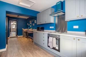 a kitchen with white cabinets and a blue wall at Room 3 plus optional additional lounge area with double sofa bed, 23 Deganwy Avenue in Llandudno